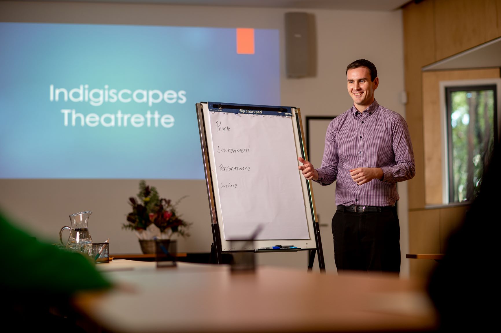 A man standing in front of a flip chart talking to people in a room.