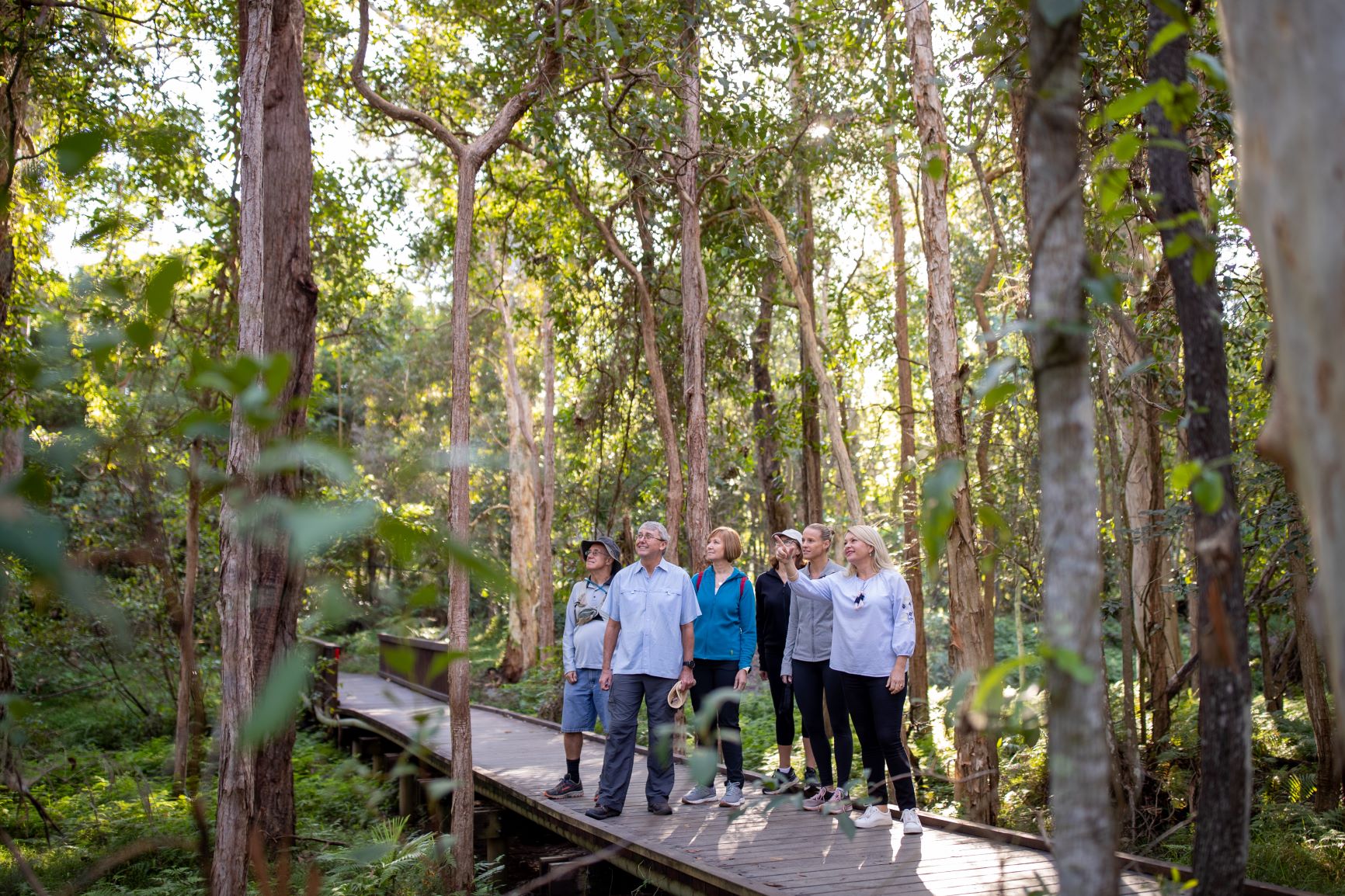 Ranger Stacey walk along a boardwalk with a group of people all surrounded by nature.